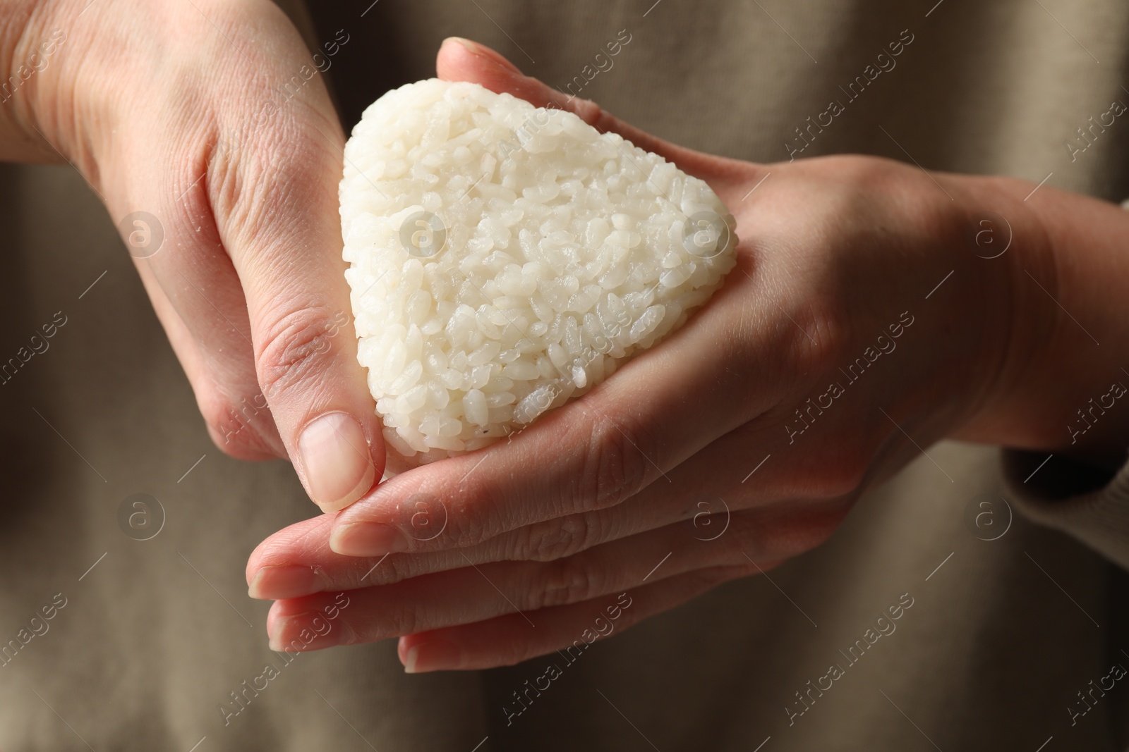 Photo of Woman with tasty onigiri (Japanese rice ball), closeup