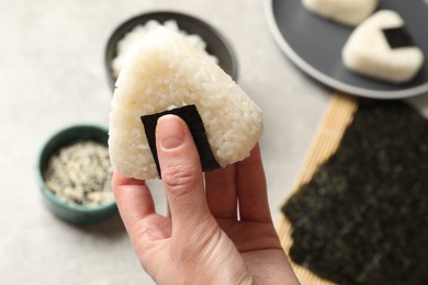 Photo of Woman with tasty onigiri (Japanese rice ball) at light table, closeup