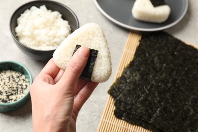 Photo of Woman with tasty onigiri (Japanese rice ball) at light table, closeup