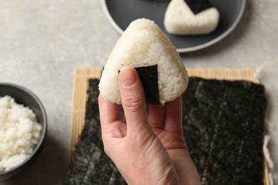 Photo of Woman with tasty onigiri (Japanese rice ball) at light table, closeup