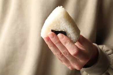 Photo of Woman with tasty onigiri (Japanese rice ball), closeup