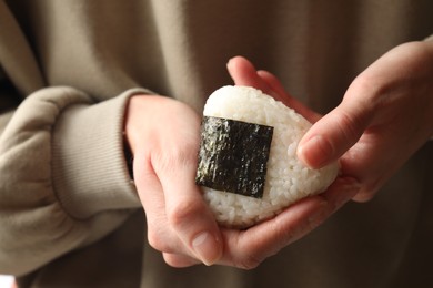 Photo of Woman with tasty onigiri (Japanese rice ball), closeup