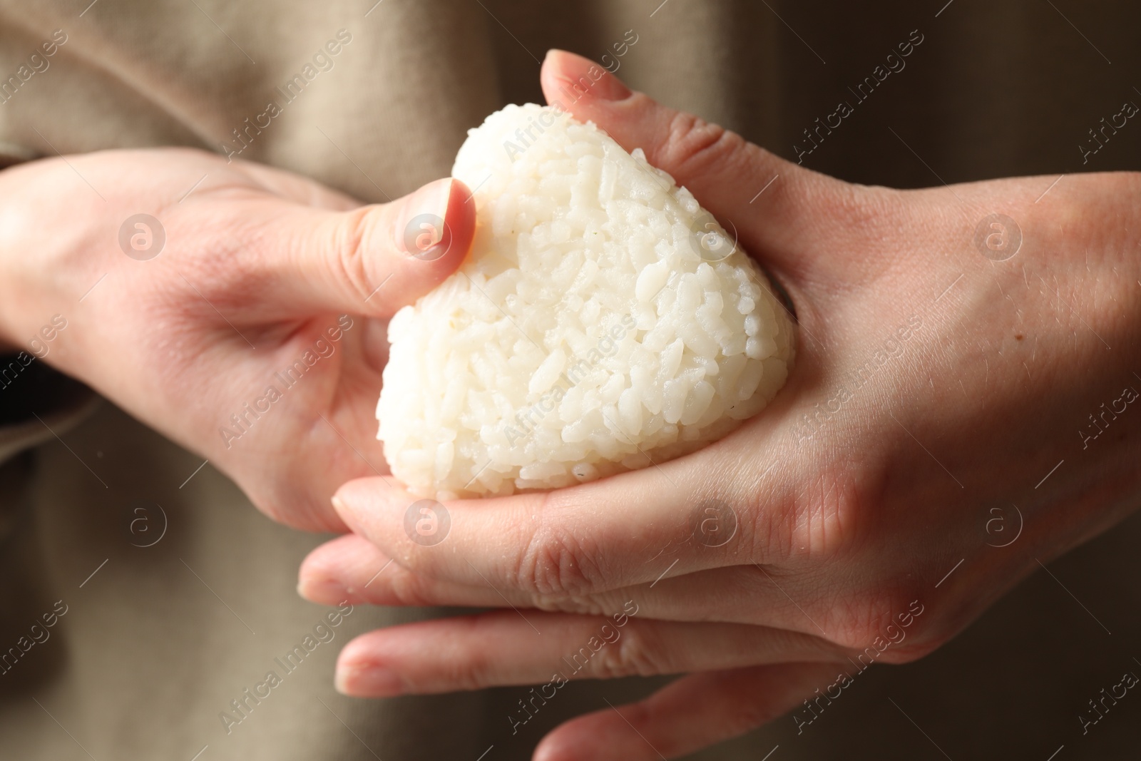 Photo of Woman with tasty onigiri (Japanese rice ball), closeup