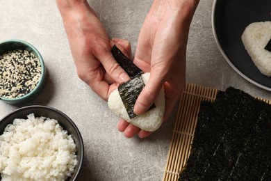 Photo of Woman making tasty onigiri (Japanese rice balls) at light table, top view