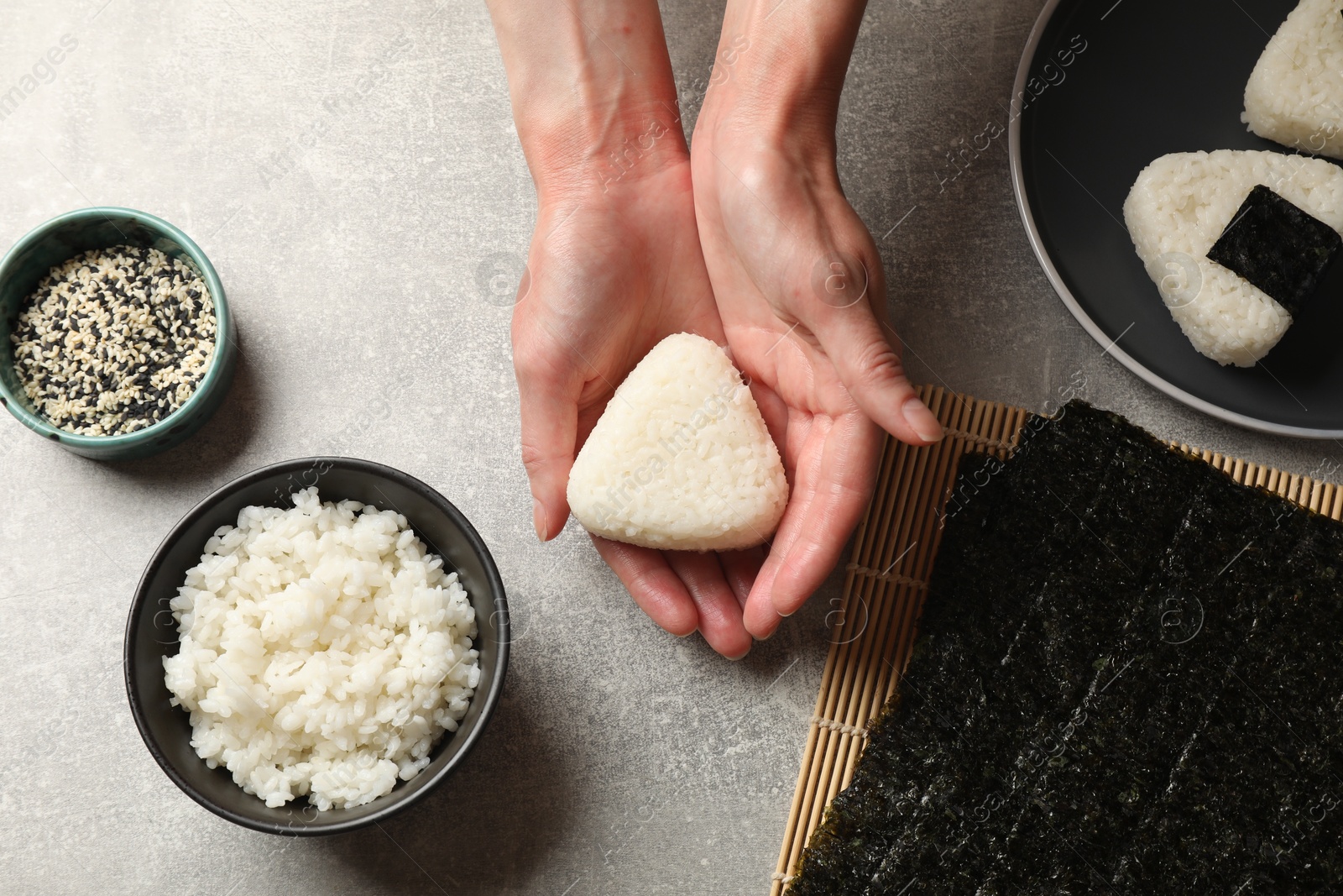 Photo of Woman making tasty onigiri (Japanese rice balls) at light table, top view