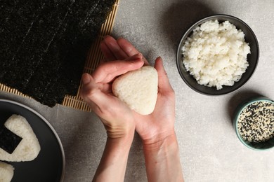 Photo of Woman making tasty onigiri (Japanese rice balls) at light table, top view