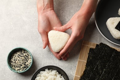 Photo of Woman making tasty onigiri (Japanese rice balls) at light table, top view