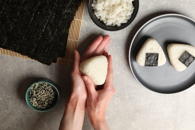 Photo of Woman making tasty onigiri (Japanese rice balls) at light table, top view