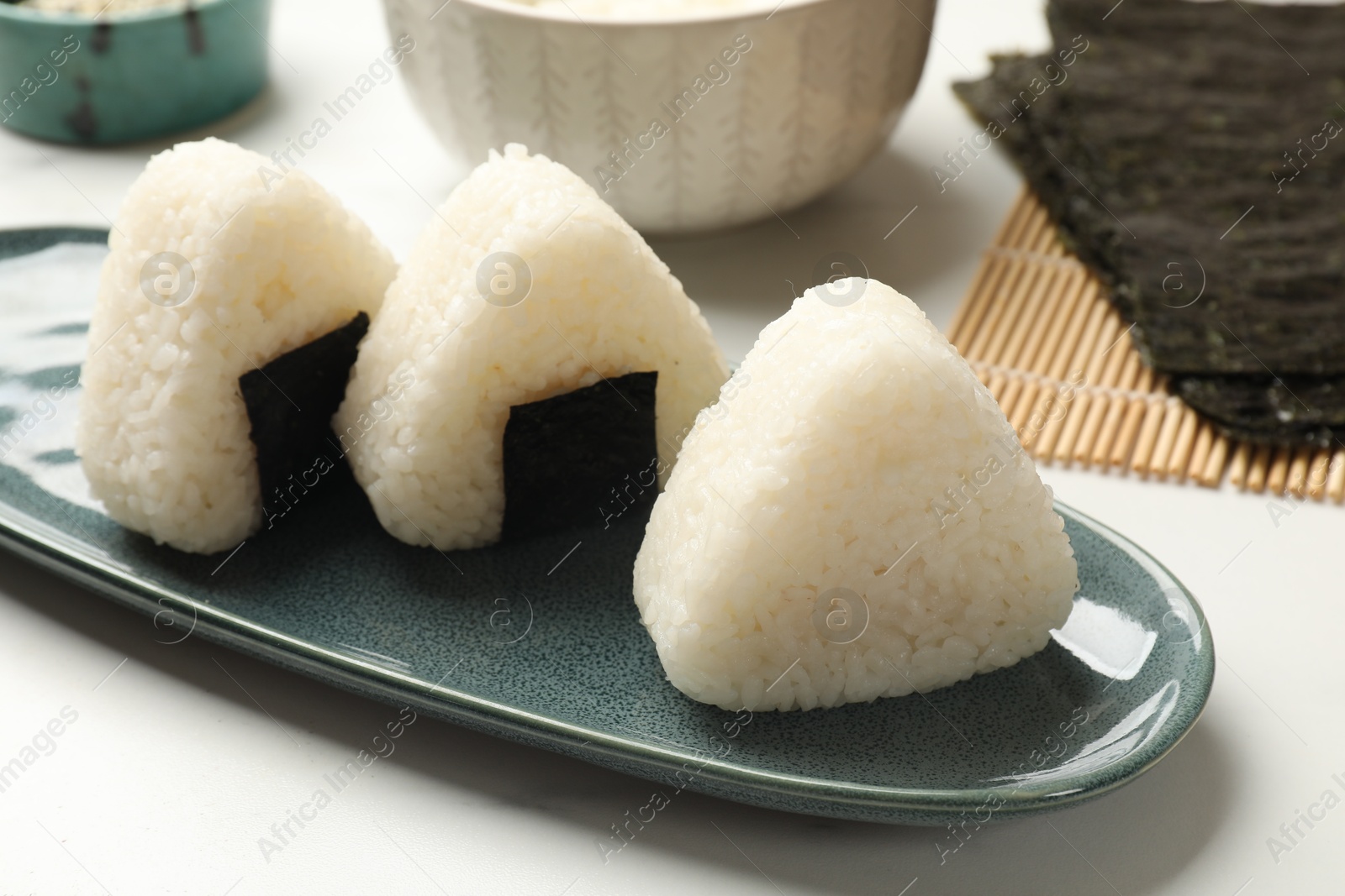 Photo of Tasty onigiri (Japanese rice balls) on white table, closeup