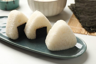 Photo of Tasty onigiri (Japanese rice balls) on white table, closeup