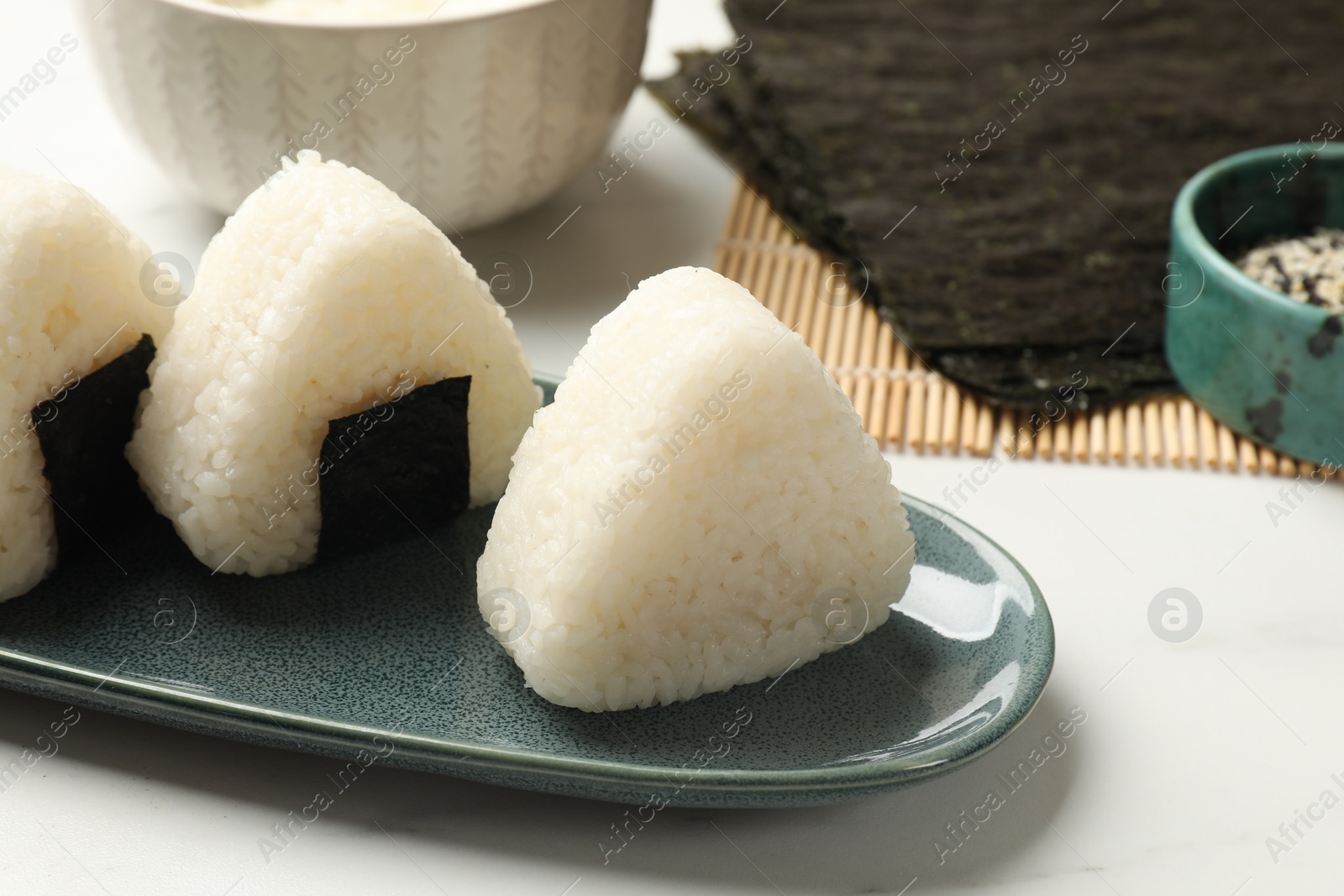 Photo of Tasty onigiri (Japanese rice balls) on white table, closeup