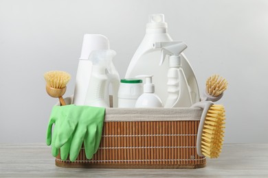 Photo of Eco-friendly cleaning products and supplies in wicker basket on wooden table