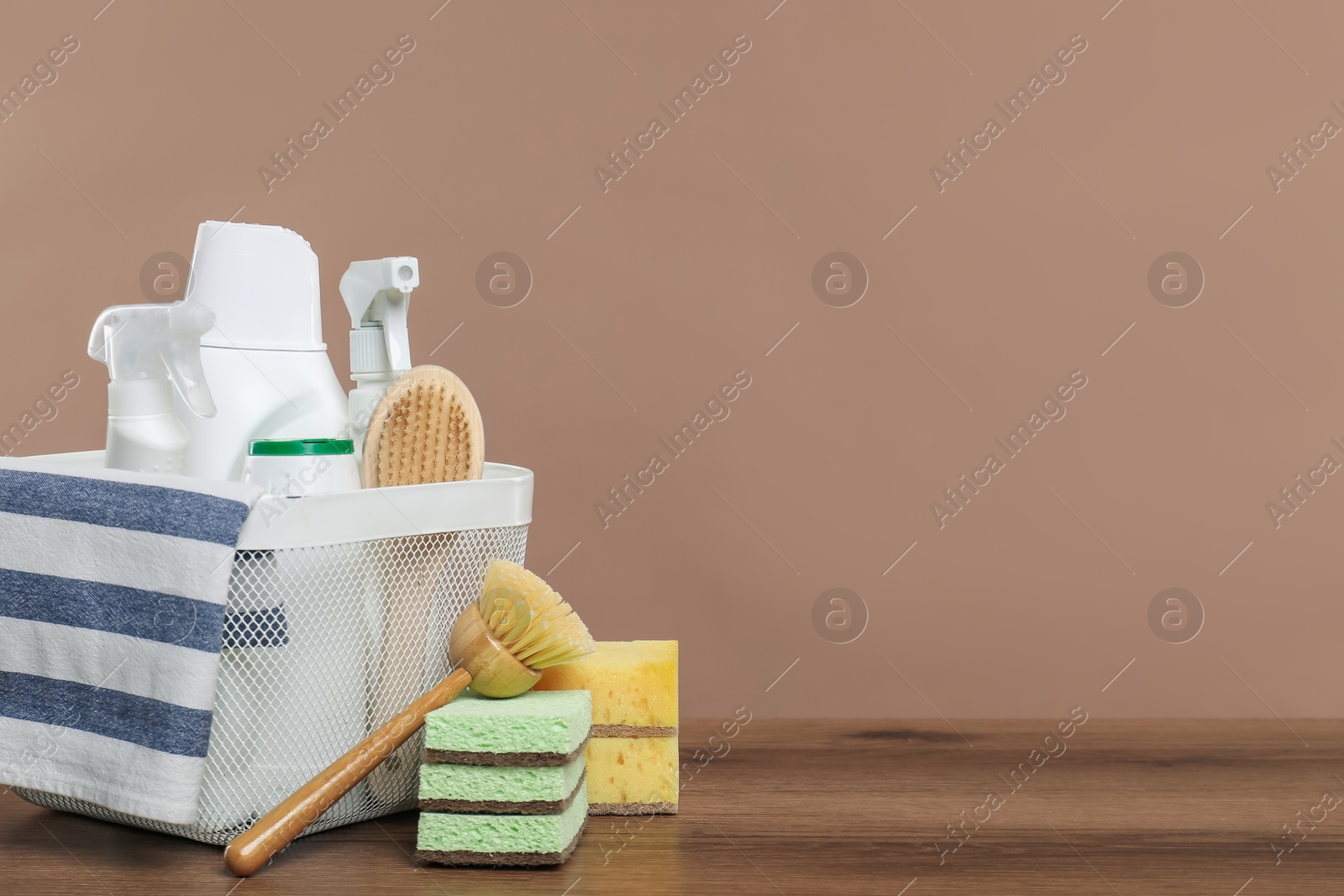 Photo of Eco-friendly cleaning products and supplies in basket on wooden table against beige background, space for text