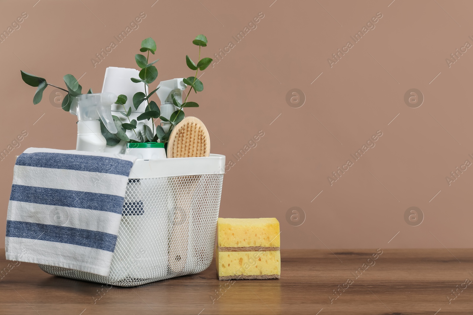 Photo of Eco-friendly cleaning products, supplies and eucalyptus branches in basket on wooden table, space for text