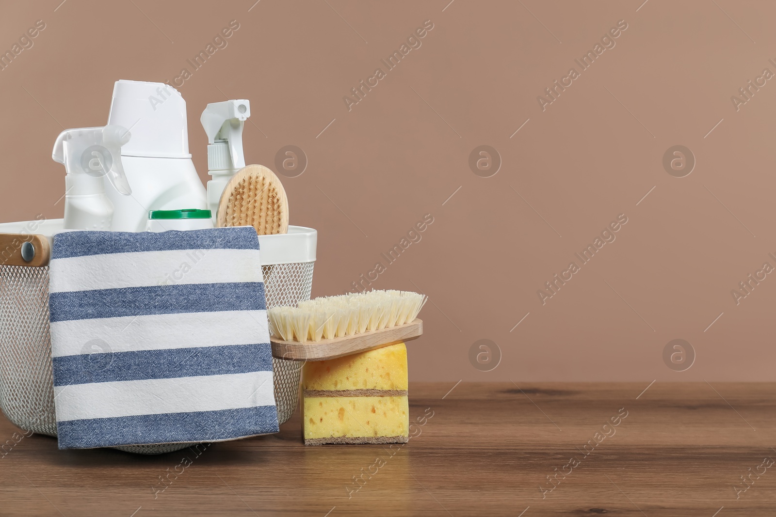 Photo of Eco-friendly cleaning products and supplies in basket on wooden table against beige background, space for text