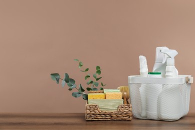 Photo of Eco-friendly cleaning products, supplies and eucalyptus branches on wooden table, space for text