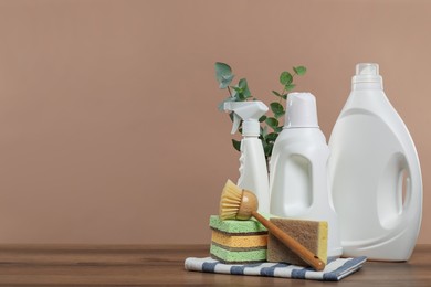 Photo of Eco-friendly cleaning products, supplies and eucalyptus branches on wooden table against beige background, space for text