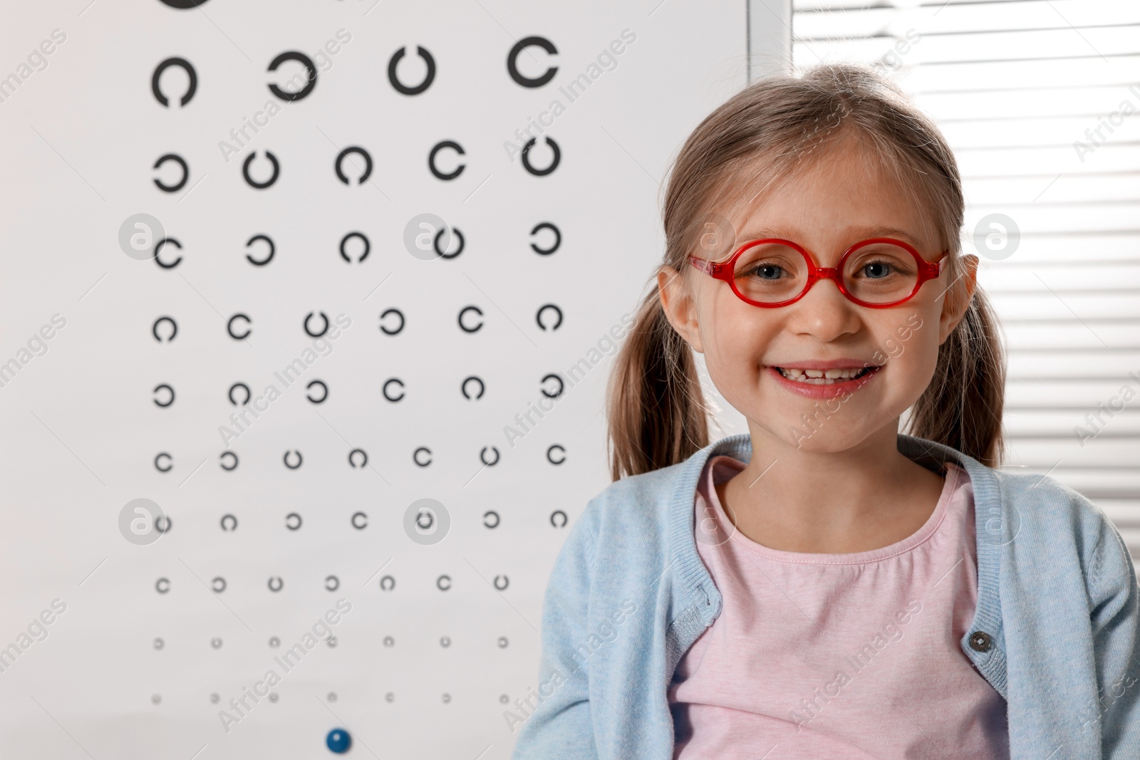 Photo of Little girl trying glasses at ophthalmologist office, space for text