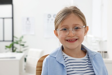 Photo of Little girl trying glasses at ophthalmologist office, space for text