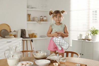 Photo of Little helper. Cute girl with oven glove in kitchen