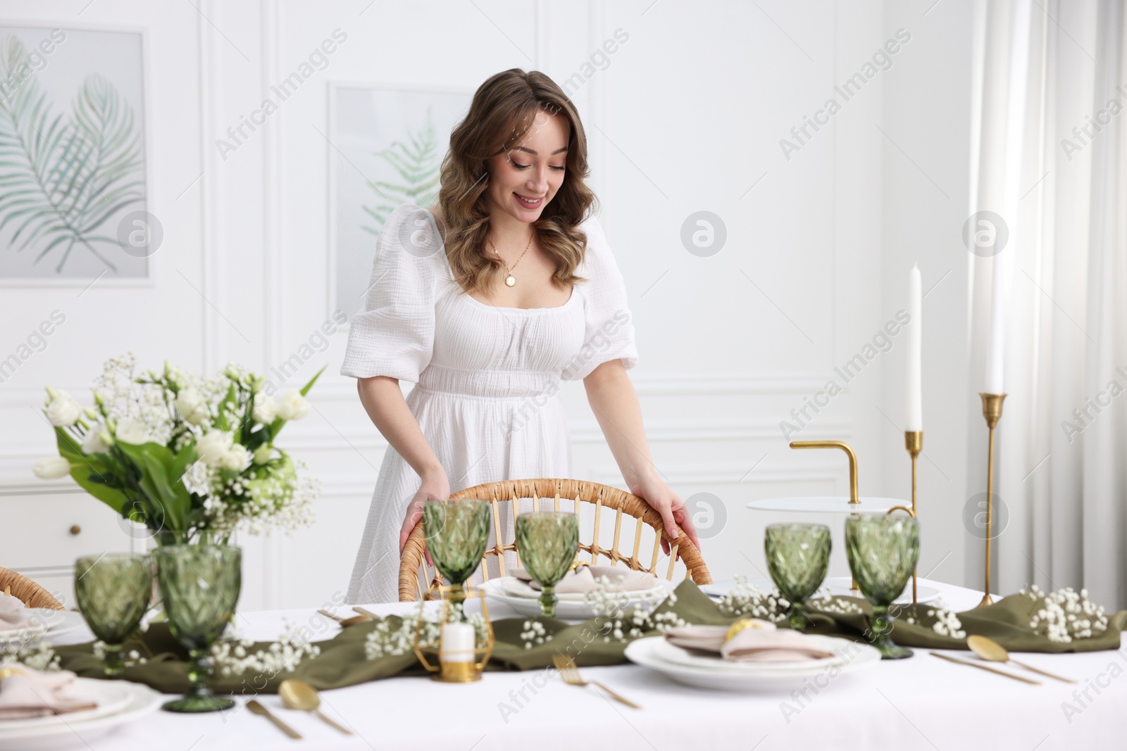 Photo of Happy young woman setting table for dinner at home