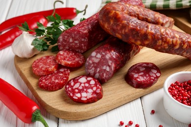 Photo of Different smoked sausages and spices on white wooden table, closeup