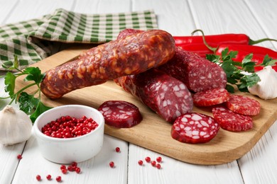 Photo of Different smoked sausages and spices on white wooden table, closeup