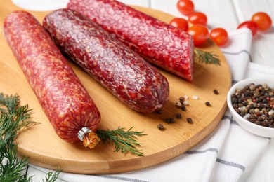 Photo of Different smoked sausages, cherry tomatoes and spices on table, closeup