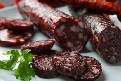 Photo of Different smoked sausages and parsley on plate, closeup