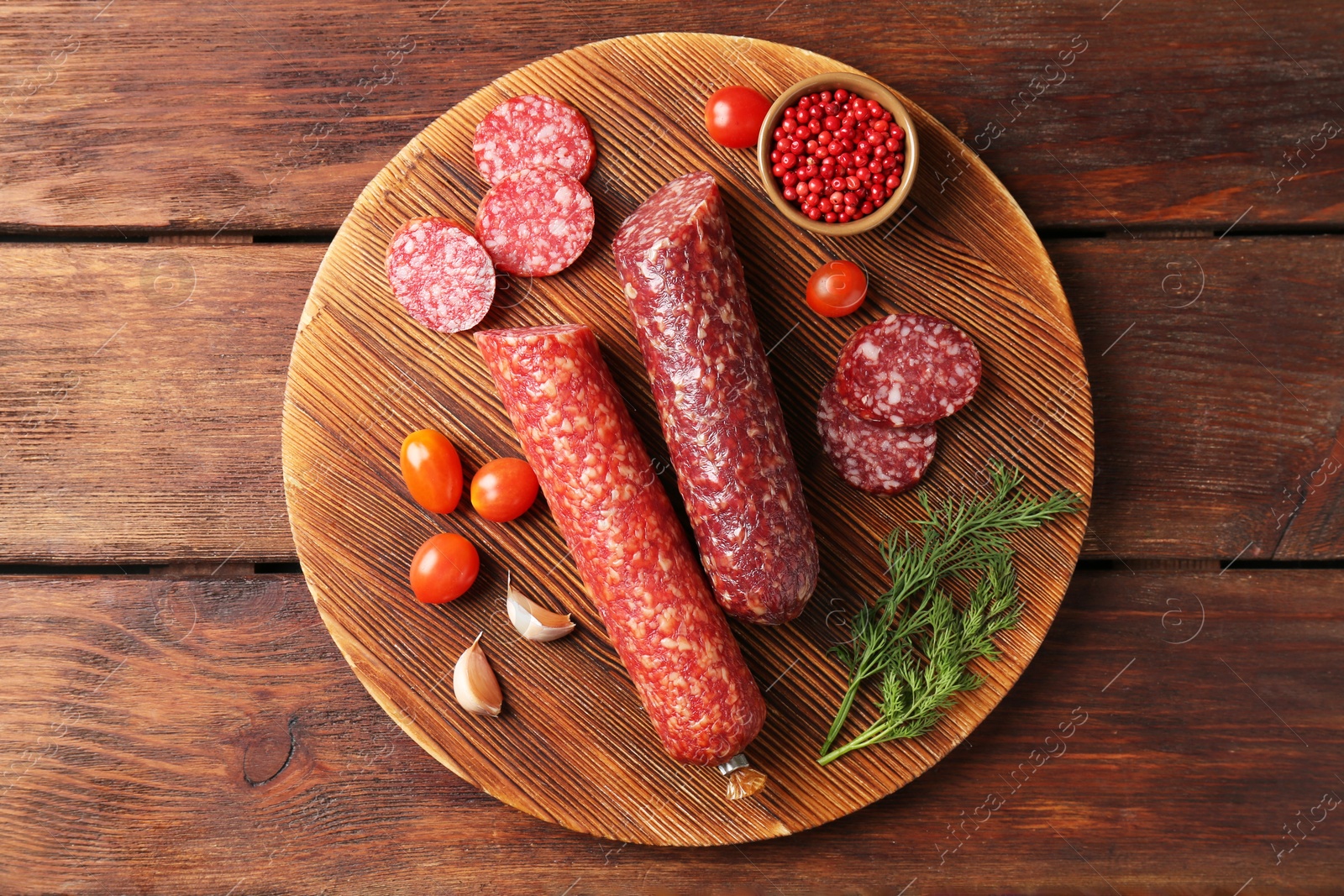 Photo of Different smoked sausages, cherry tomatoes and spices on wooden table, top view