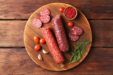 Photo of Different smoked sausages, cherry tomatoes and spices on wooden table, top view