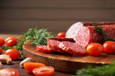 Photo of Different smoked sausages, cherry tomatoes and spices on table, closeup