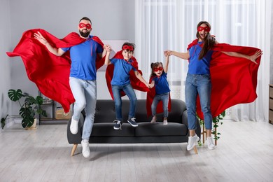 Photo of Parents and their children in superhero costumes jumping at home