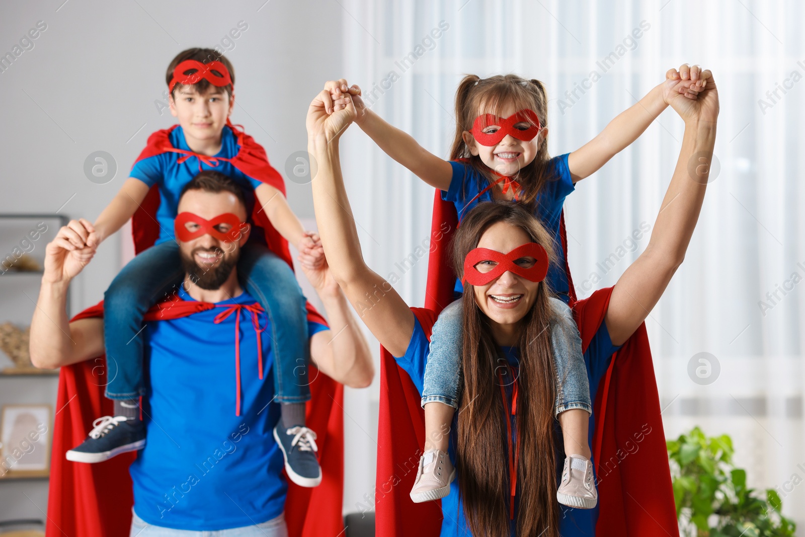 Photo of Parents and their children wearing superhero costumes at home