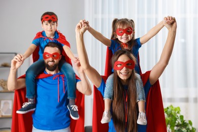 Photo of Parents and their children wearing superhero costumes at home