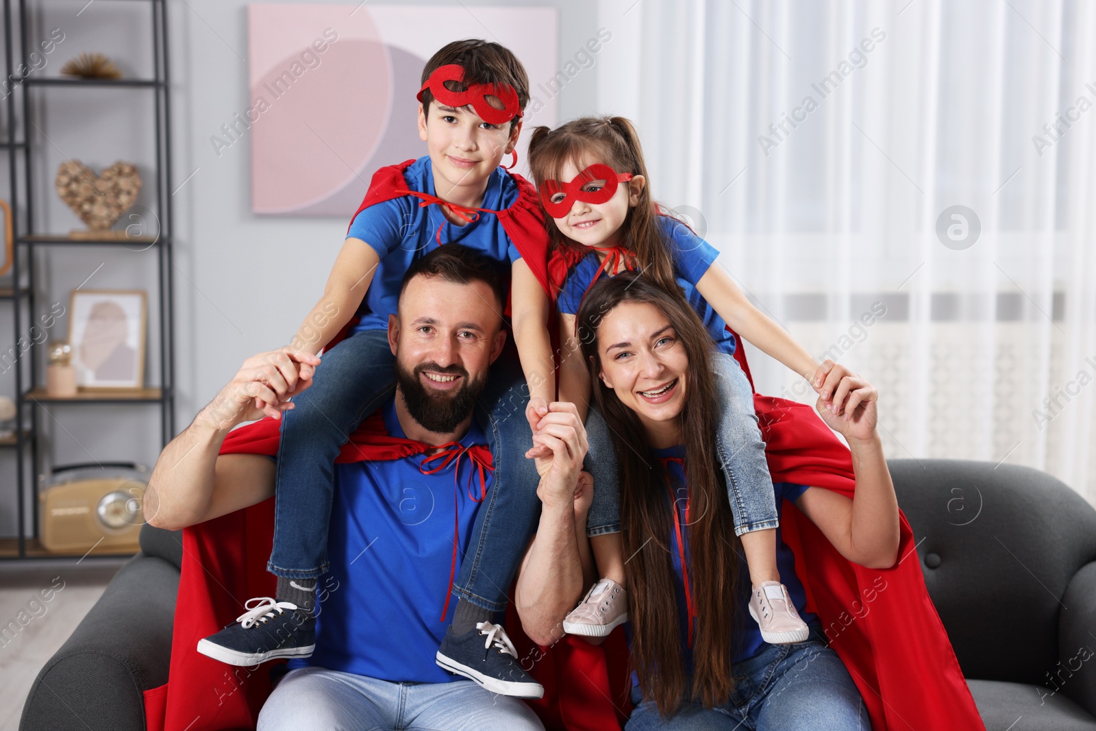 Photo of Parents and their children wearing superhero costumes at home