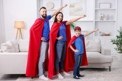 Photo of Parents and their son wearing superhero costumes at home