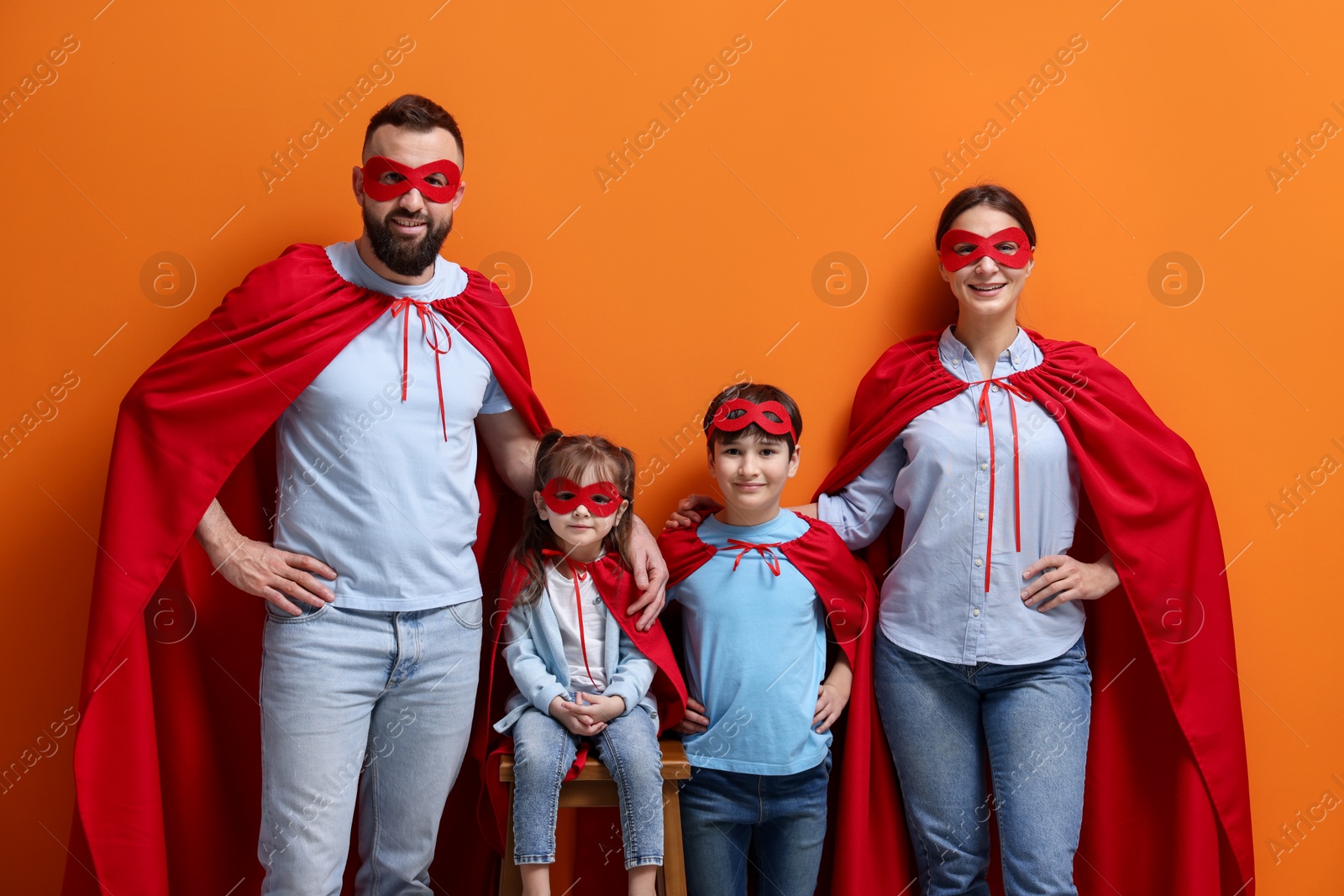 Photo of Parents and their children wearing superhero costumes on red background