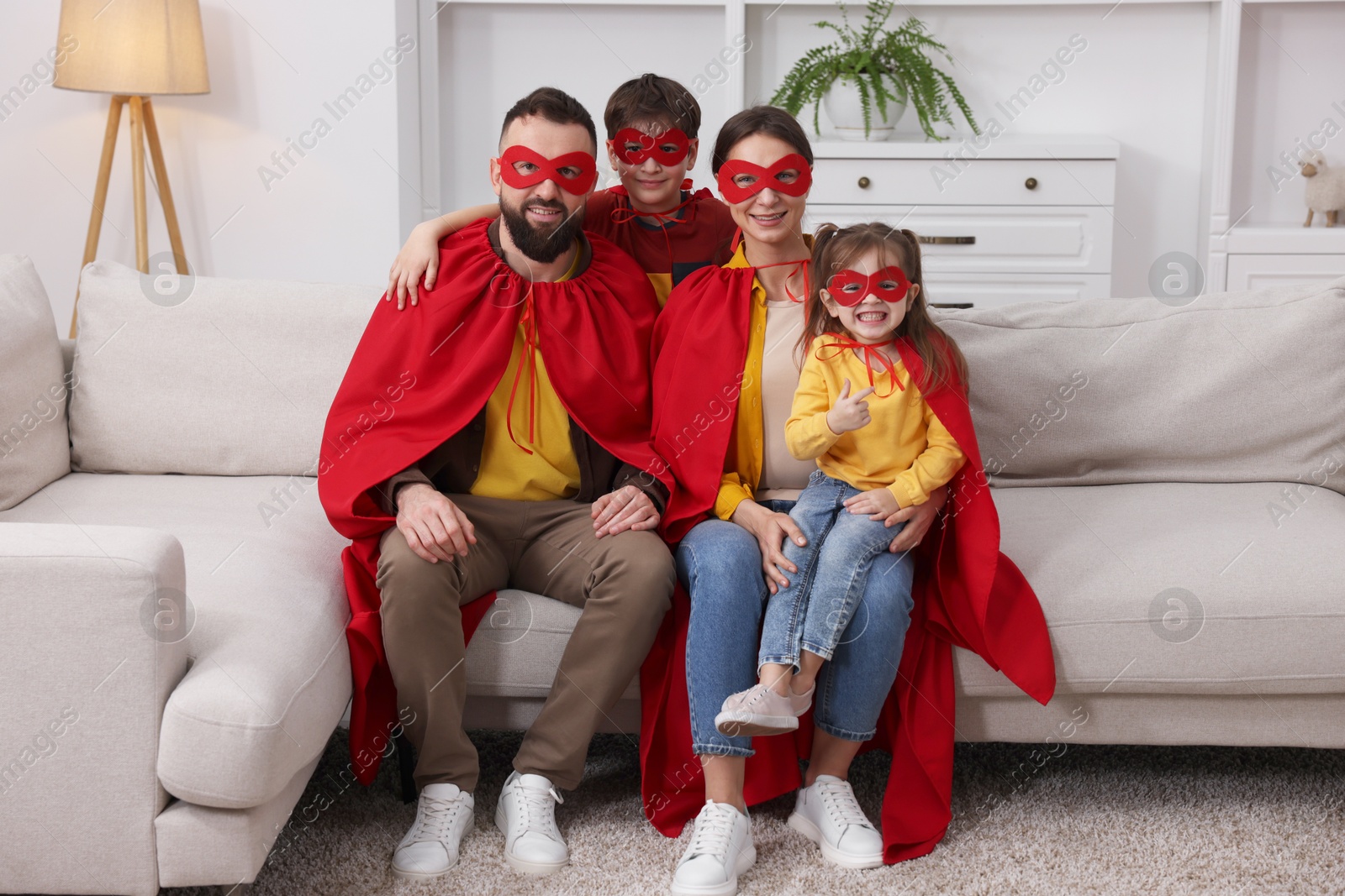 Photo of Parents and their children wearing superhero costumes at home