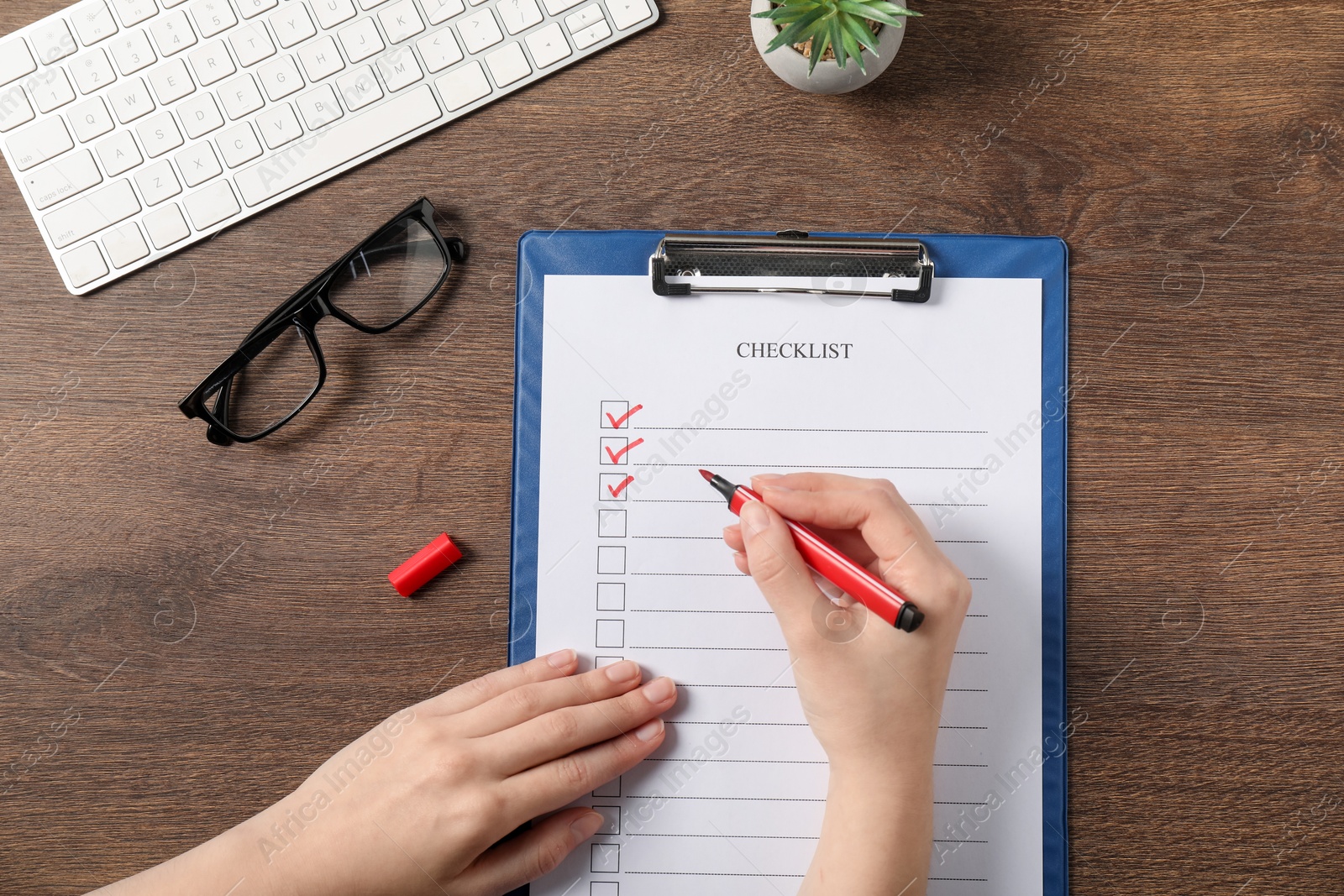 Photo of Woman filling Checklist at wooden table, top view