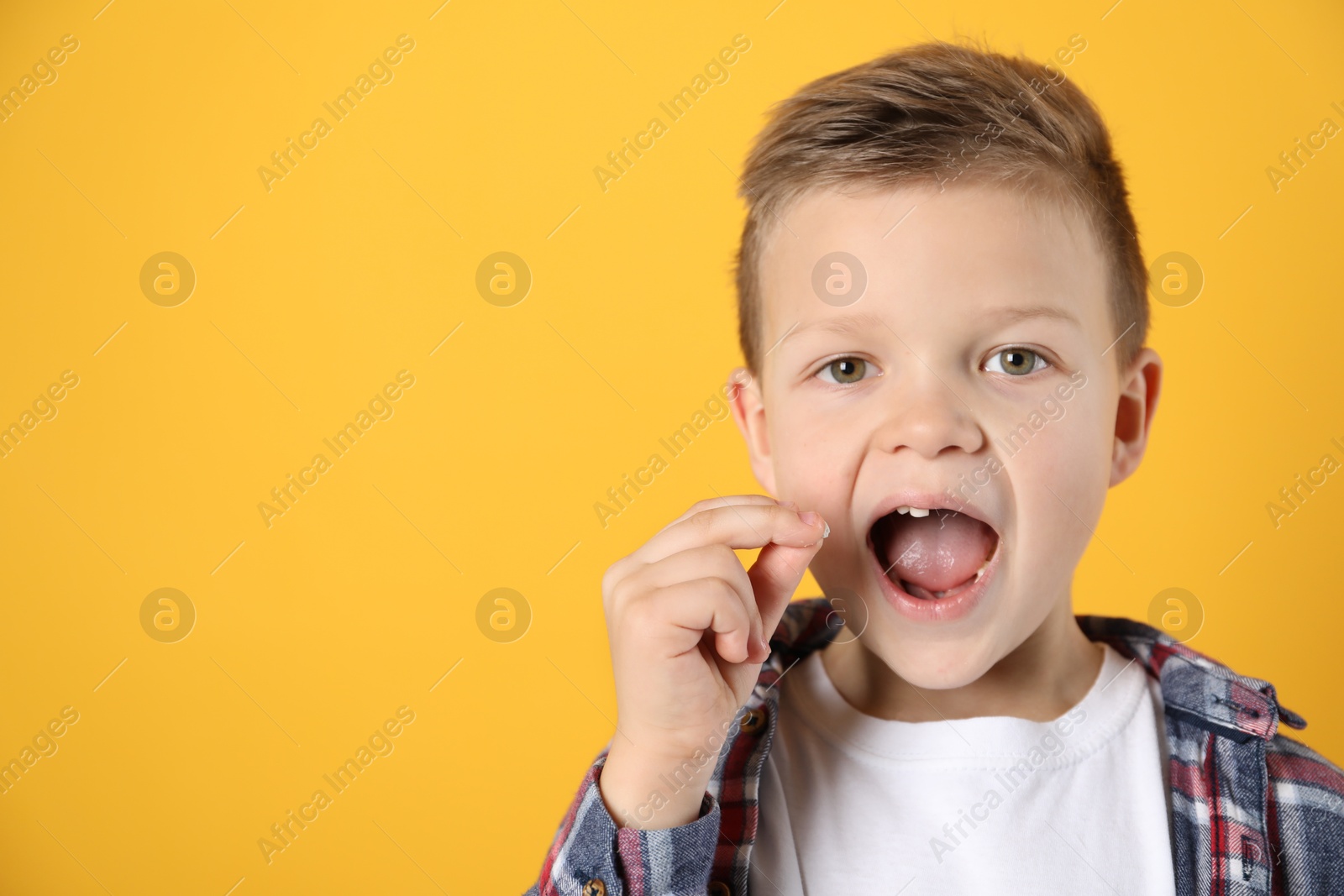 Photo of Cute little boy with missing tooth on orange background, space for text. Waiting for tooth fairy