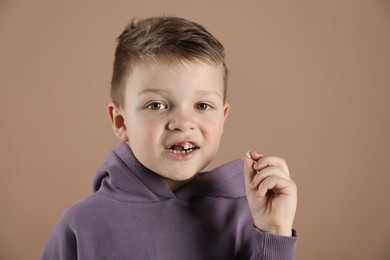 Cute little boy with missing tooth on dark beige background. Waiting for tooth fairy