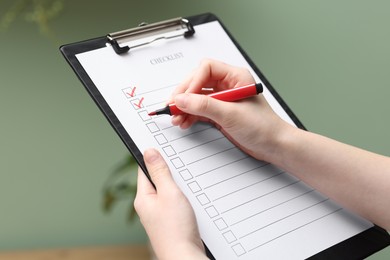 Photo of Woman filling Checklist with marker indoors, closeup