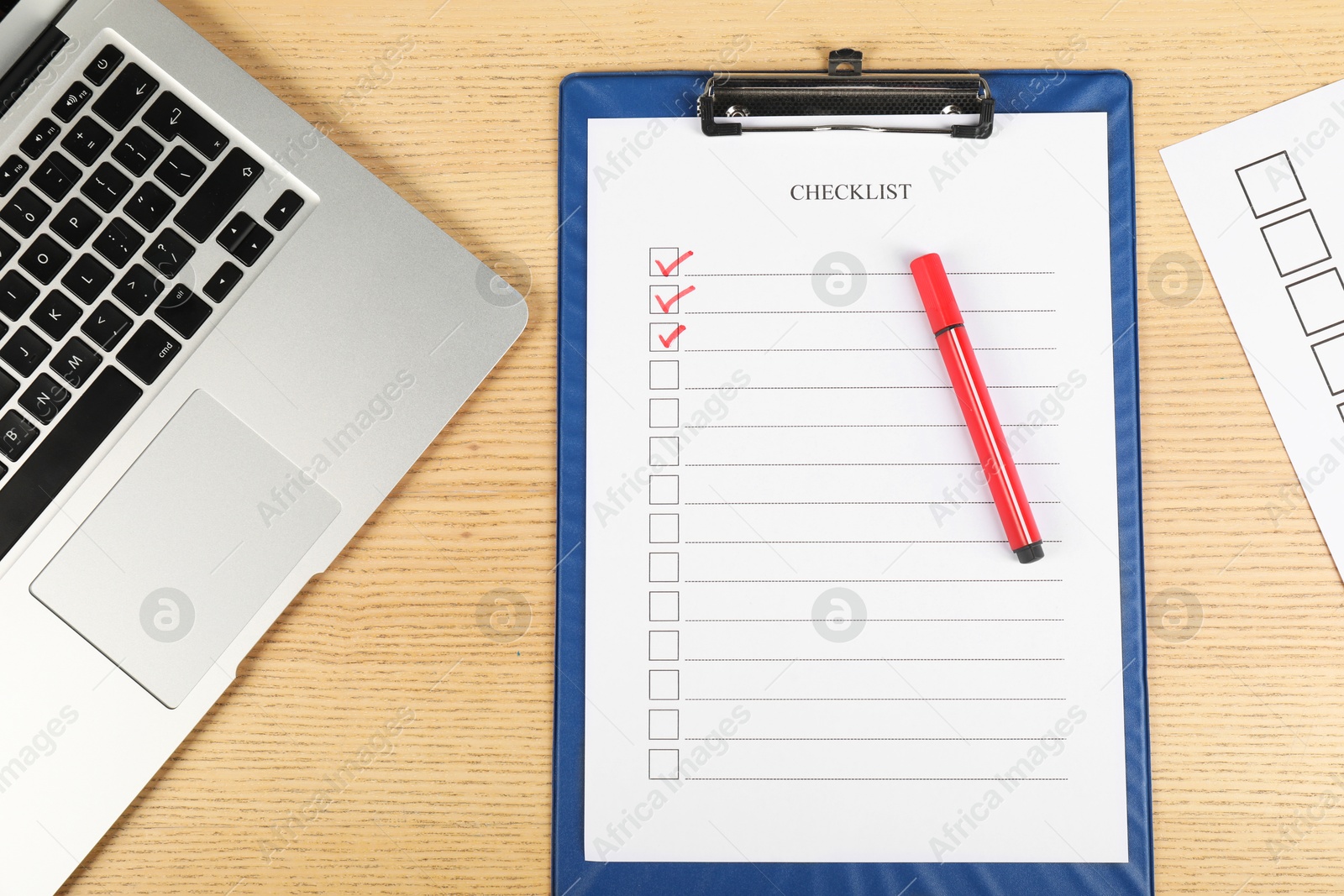 Photo of Checklist with checkboxes, marker and laptop on wooden table, flat lay