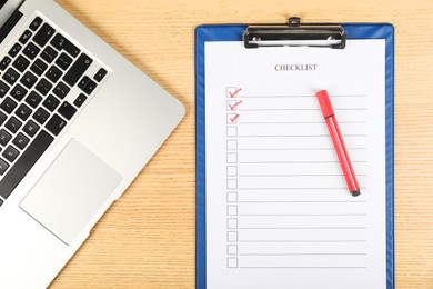 Photo of Checklist with checkboxes, marker and laptop on wooden table, flat lay