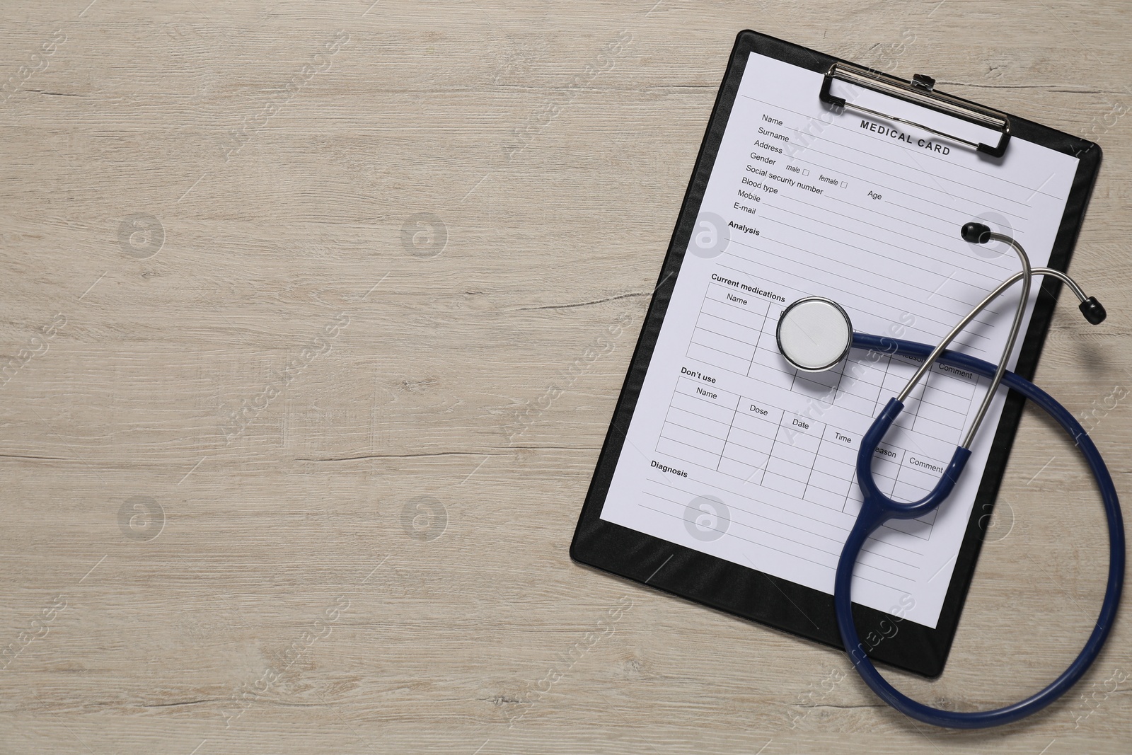 Photo of Medical card form and stethoscope on light wooden background, top view. Space for text