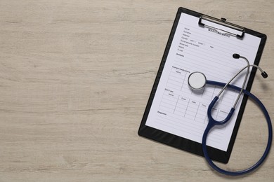 Medical card form and stethoscope on light wooden background, top view. Space for text