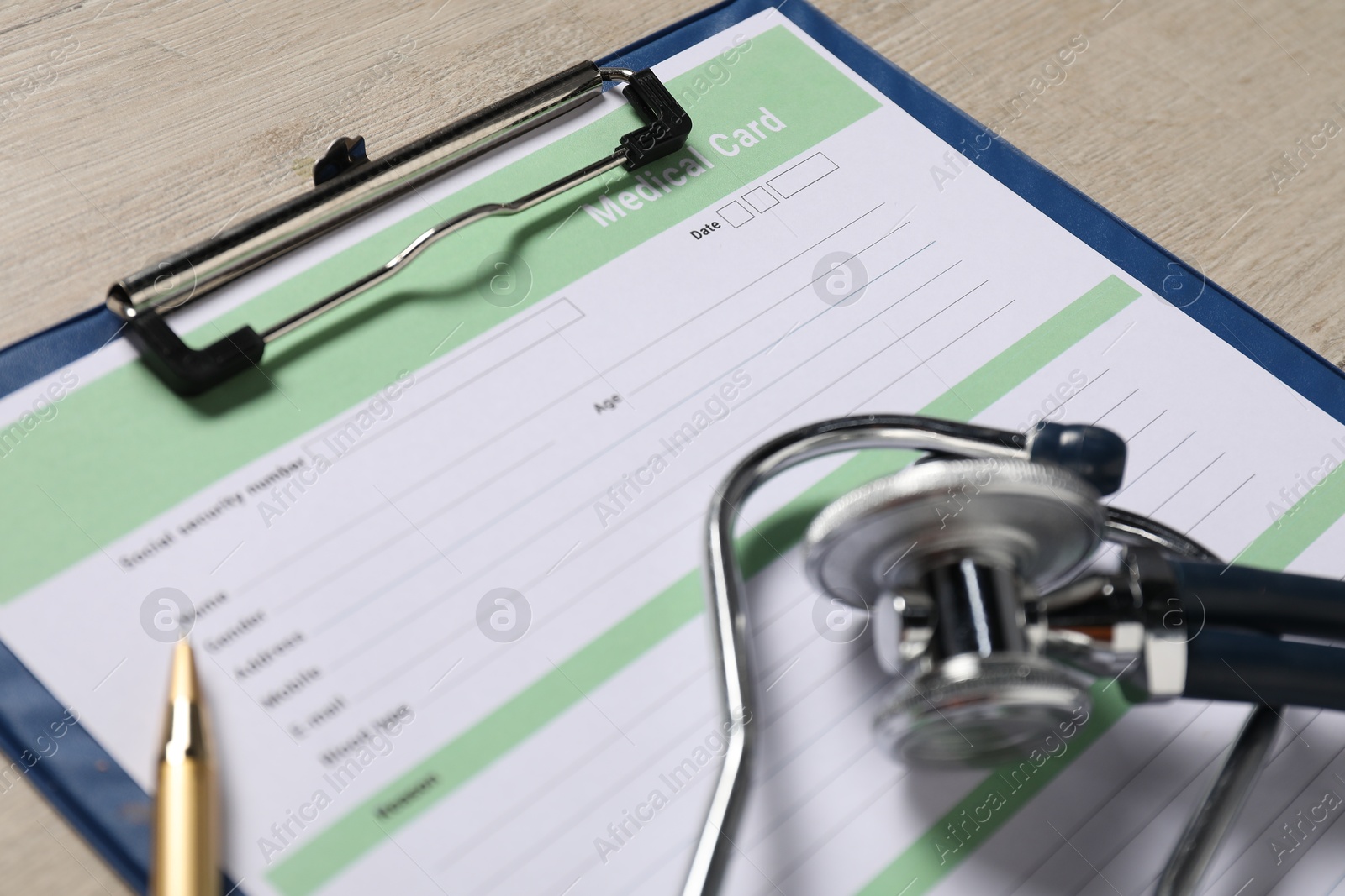 Photo of Medical card form, pen and stethoscope on light wooden background, closeup