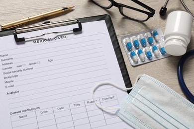 Composition with medical card form on light wooden background, closeup