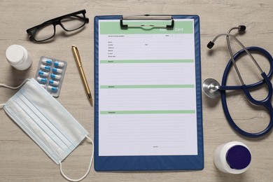 Flat lay composition with medical card form on light wooden background